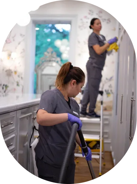 A Vella housekeeper on a ladder, vacuuming high corners