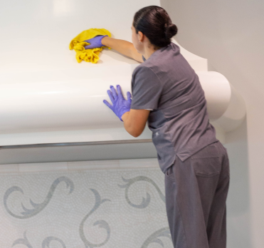 A Vella housekeeping agent cleaning chimney while climbing on a stool.