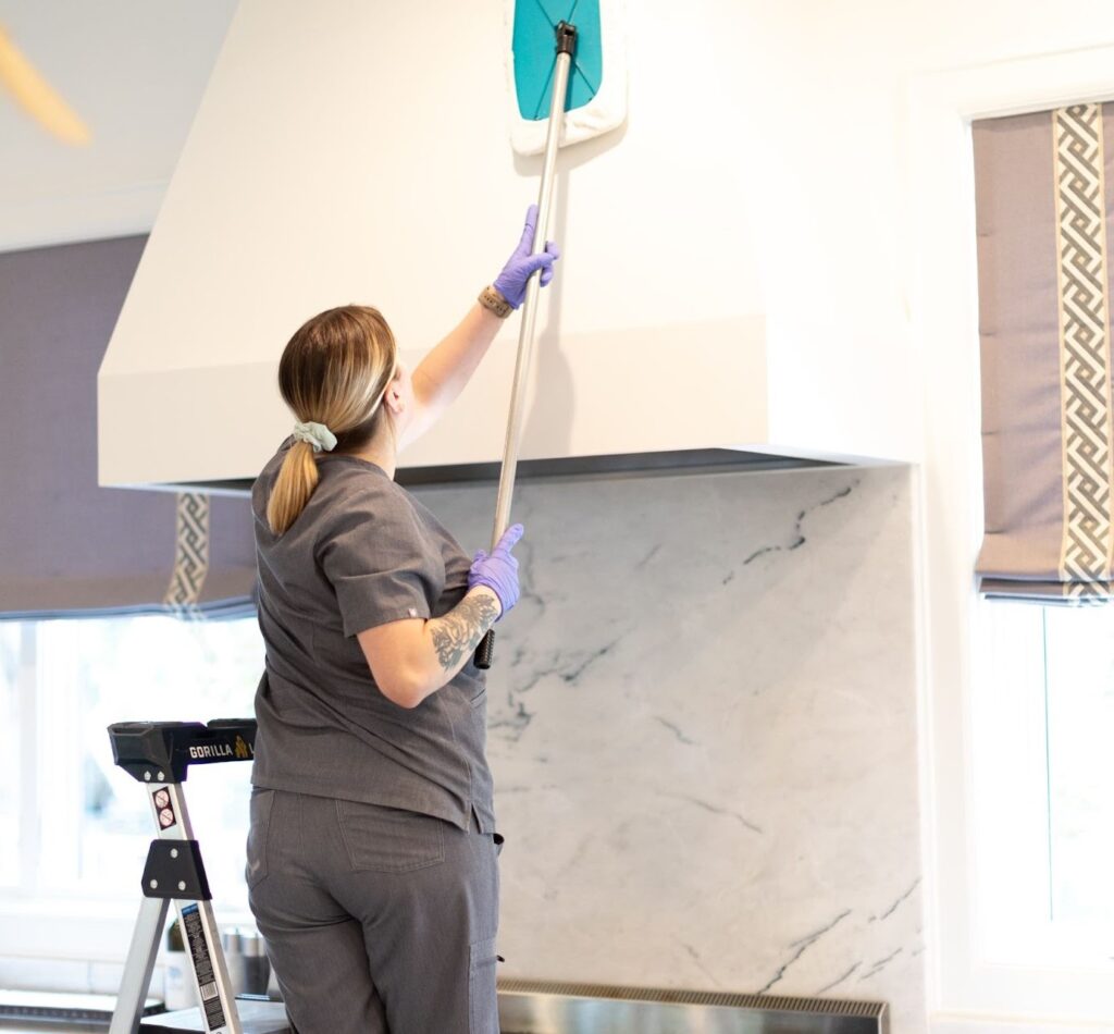 "Cleaner using a microfiber mop to clean a kitchen hood, showcasing tips for efficiently cleaning your kitchen."