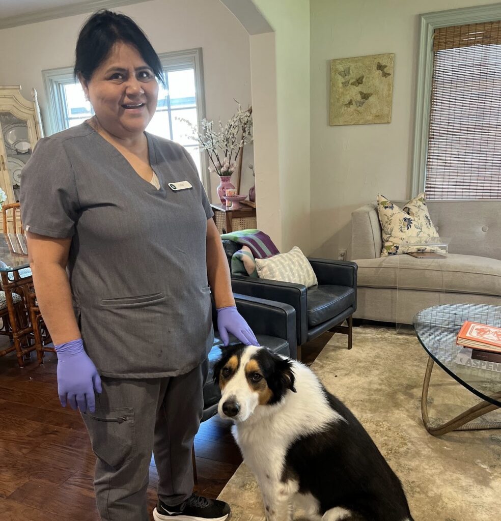 A smiling professional cleaner poses with a dog in a tidy living room, showing the comprehensive care involved when you deep clean your kitchen