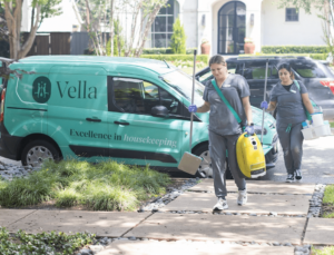 Two professional cleaners walking from a teal van, carrying equipment and ready to provide expert cleaning services, including cleaning your microwave.