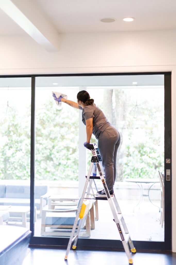 Vella professional cleaning interior window pane with a microfiber cloth after construction in Texas.