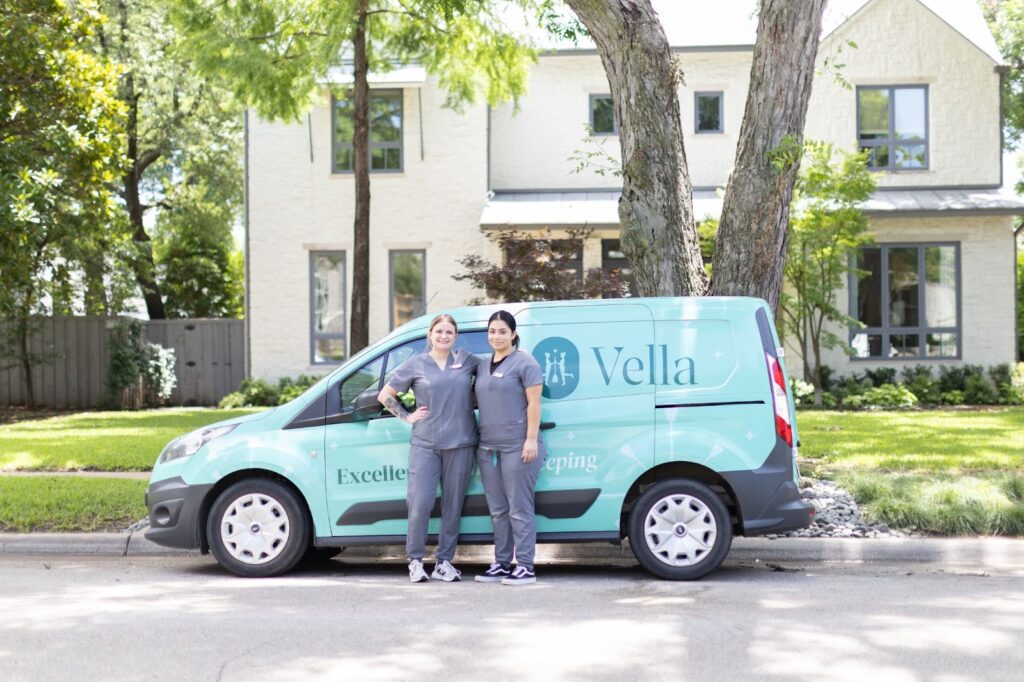 Two Vella cleaning staff standing in front of a Vella Clean van parked outside a home in Texas, offering professional cleaning services.