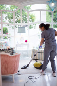Vella cleaning professional vacuuming a bright Texas home as part of deep floor cleaning services.