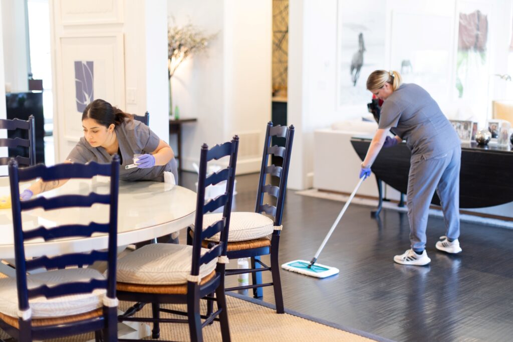 Vella cleaning team sanitizing a living room table and floor in a Fort Worth, Texas home using eco-friendly products.