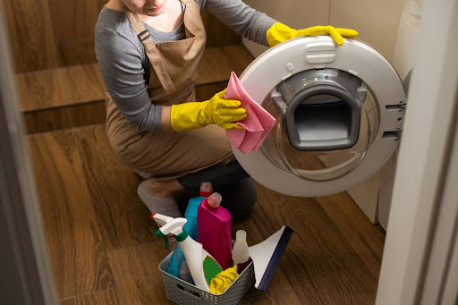 A Vella cleaning staff member cleaning a washing machine with a microfiber cloth inside a home in Austin.