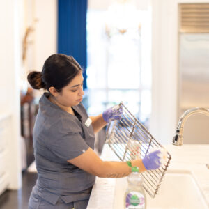 Vella technician scrubs grill grate with non-toxic soap in a sink, prepping it for safe, flavor-neutral grilling.