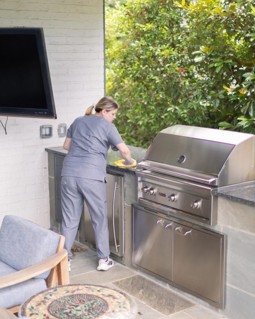 A Vella professional thoroughly cleaning a shared barbecue grill in a condo community.