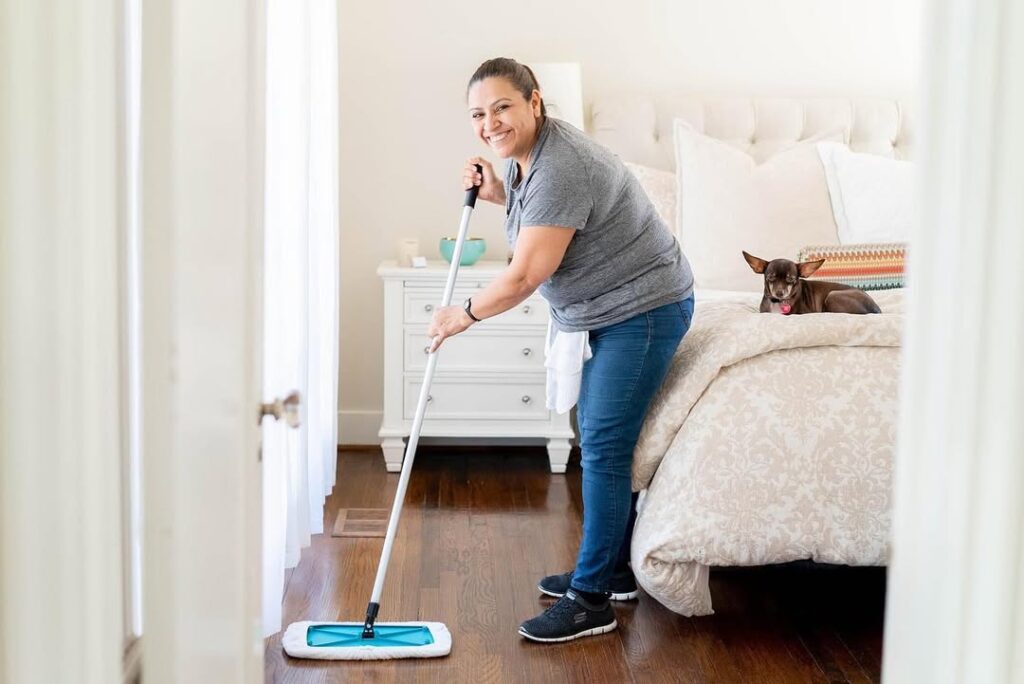 Vella Cleaning professional cleaning a wooden floor with a mop.