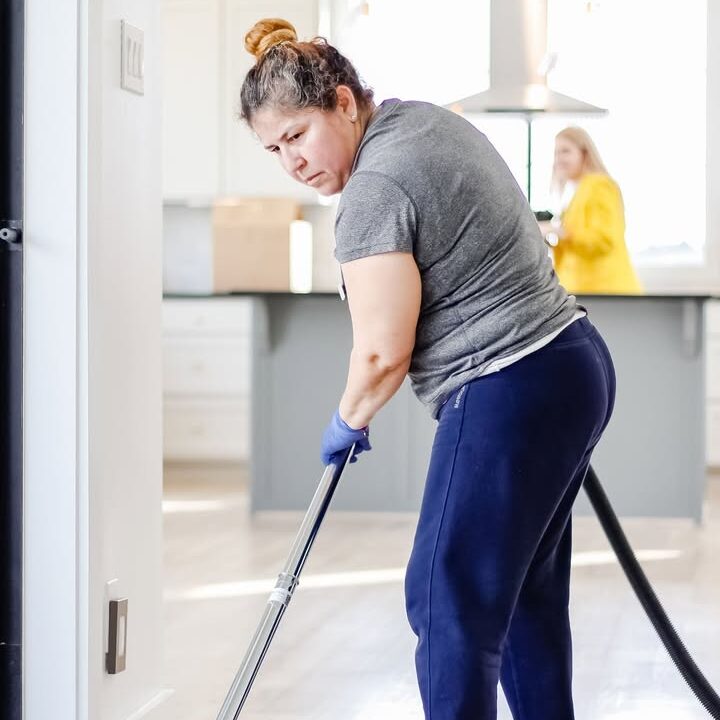 Vella professional cleaner vacuuming a floor with reusable tools, showcasing zero-waste cleaning practices.