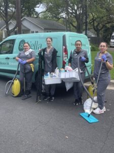 A team of four professional cleaners in uniform posing with their equipment in front of a company van.
