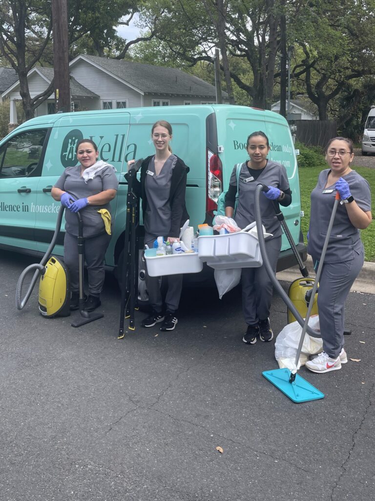 Four professional cleaners from Vella holding their tools.