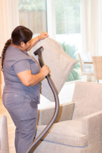 Professional Vella cleaner vacuuming a couch cushion in a home in Austin, Texas.