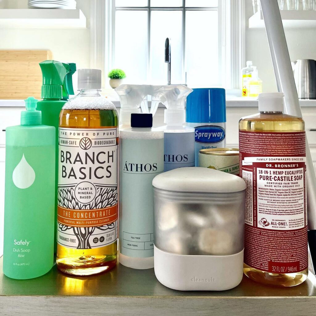 Non-toxic, eco-friendly cleaning products including reusable bottles and plant-based solutions arranged neatly on a surface.