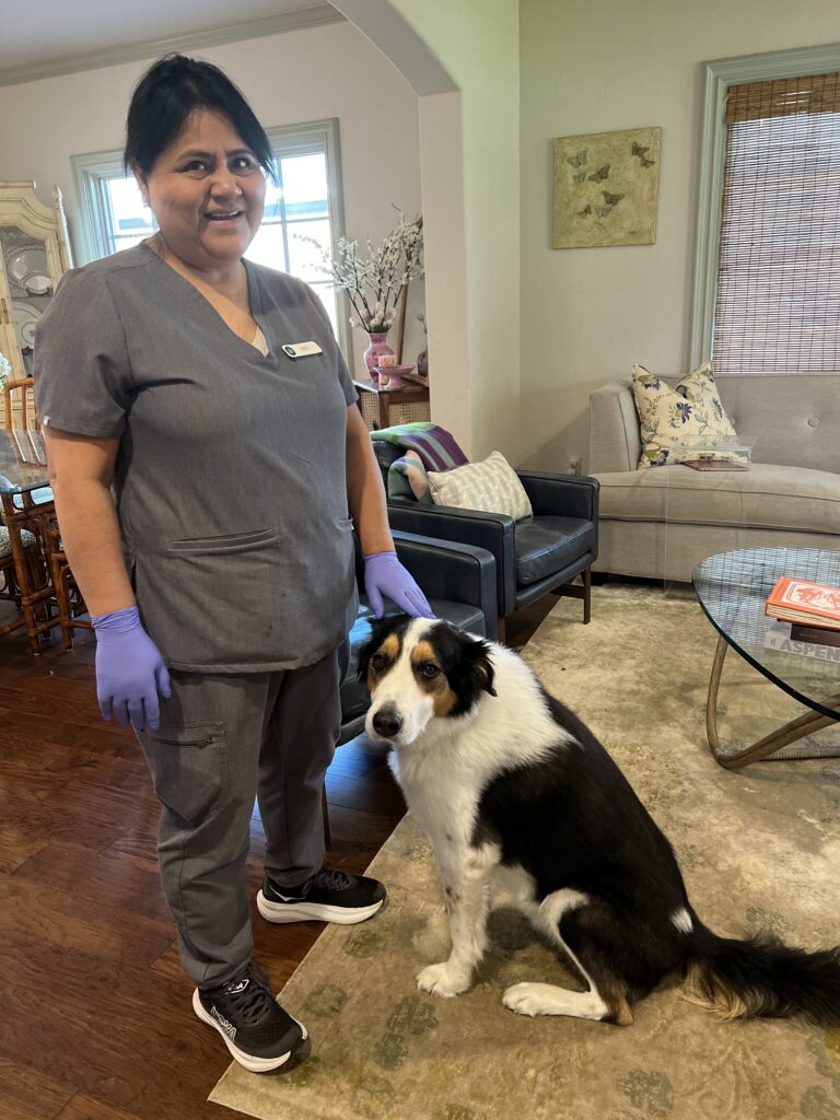 Two Vella cleaning professionals posing with a friendly pet dog during a residential cleaning service in Dallas.